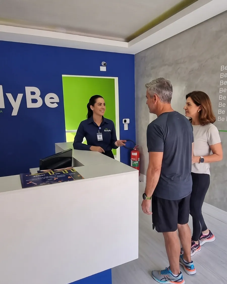 Recepcionista da BodyBe acolhendo um casal de clientes